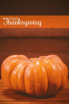 Thanksgiving greeting text against pumpkin on wooden table during halloween