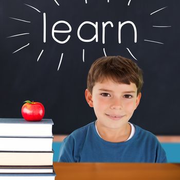 The word learn and cute boy smiling against red apple on pile of books in classroom