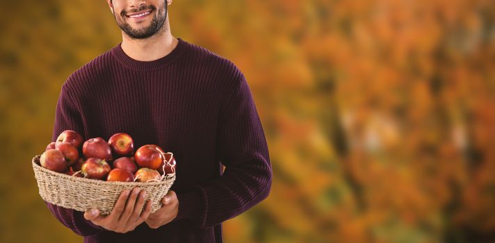 Portrait of man holding basket with apples against tree growing outdoors