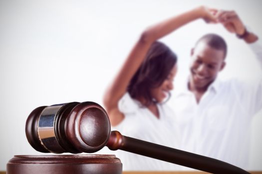 Romantic couple dancing and smiling against hammer and gavel