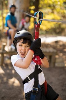 Smiling cute boy enjoying zip line adventure on sunny day