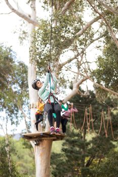 Woman enjoying zip line adventure in park on a sunny day