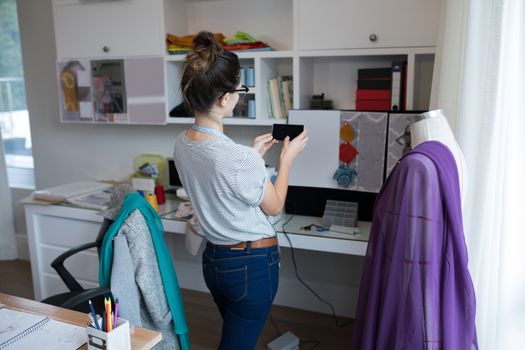 Fashion designer taking photo with mobile phone at home