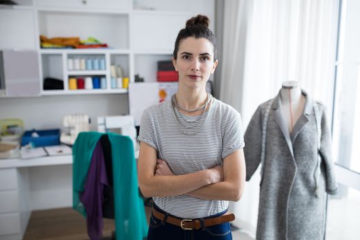 Fashion designer standing with arms crossed at home