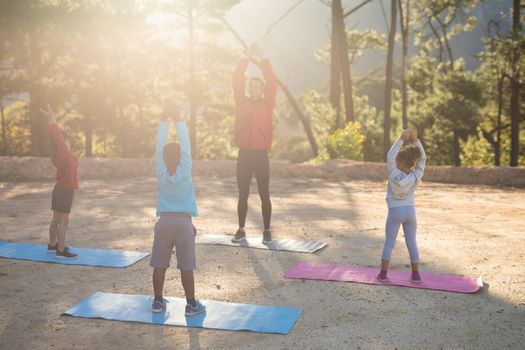 Coach assisting kids in practicing yoga on a sunny day