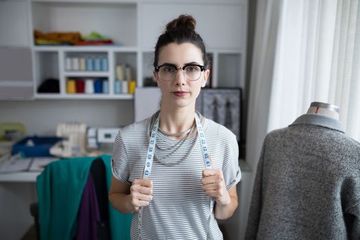 Fashion designer standing with measuring tape at home