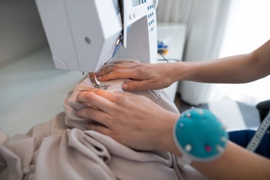 Fashion designer using sewing machine at home