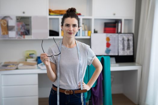 Fashion designer standing with hand on hip at home
