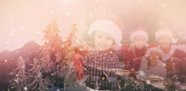 View of landscape during snowfall against son wearing santa hat holding baubles in front of his family