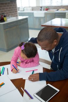 Father helps his daughter with her school homework at home