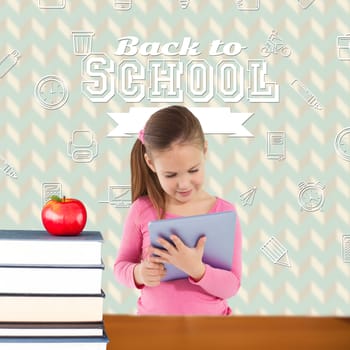 Cute girl using tablet against red apple on pile of books