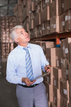 Warehouse manager checking his inventory in a large warehouse