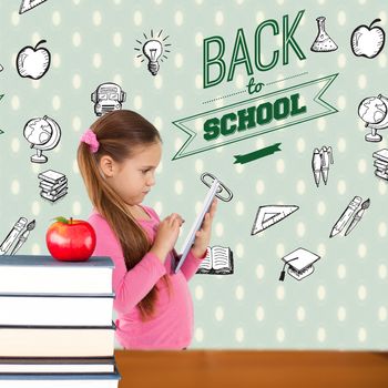 Cute girl using tablet against red apple on pile of books