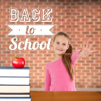 Cute girl with hand out against red apple on pile of books