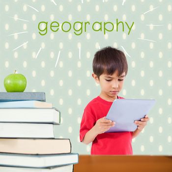 The word geography and cute boy using tablet against red apple on pile of books