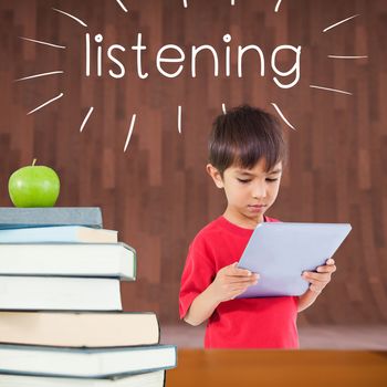 The word listening and cute boy using tablet against red apple on pile of books