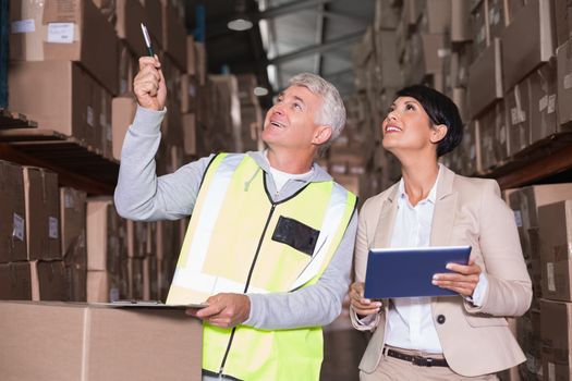 Pretty warehouse manager talking to foreman in a large warehouse