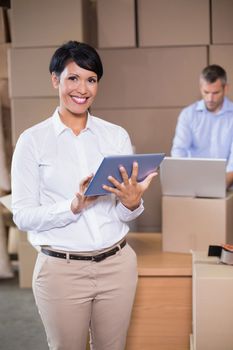 Pretty warehouse manager using tablet pc in a large warehouse