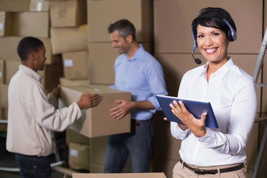 Pretty warehouse manager using tablet during busy period in a large warehouse