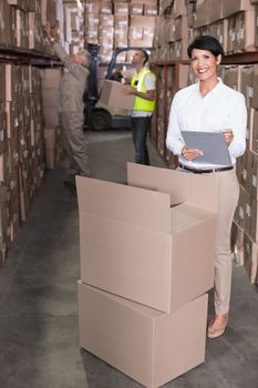 Pretty warehouse manager writing on clipboard in a large warehouse