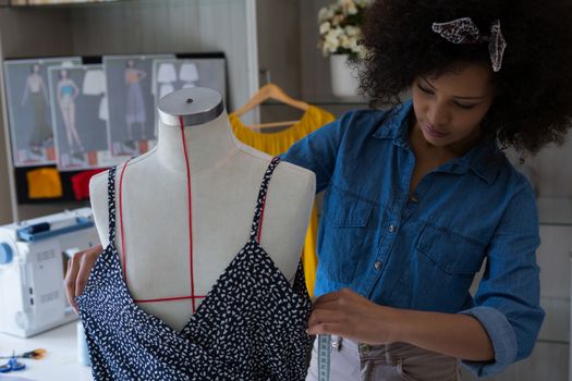 Fashion designer designing a dress on mannequin at home