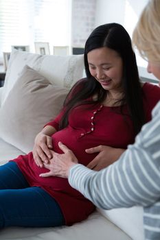 Happy female friends feeling the presence of baby in stomach