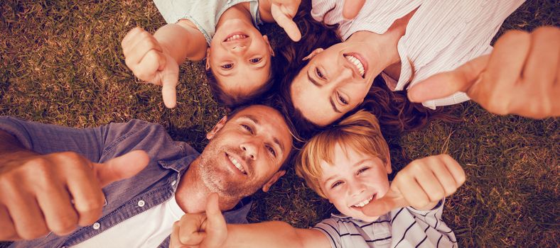 Portrait of happy family in park together gesturing thumbs up