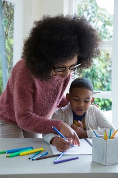  Mother helping her son in doing homework at home