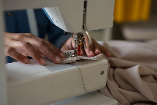 Close-up of fashion designer stitching cloth in sewing machine