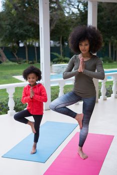 Mother and daughter performing yoga in the porch at home