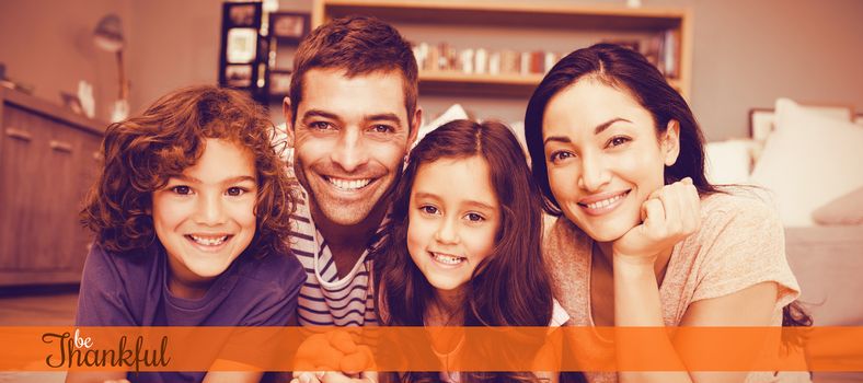 Thanksgiving greeting text against portrait of happy family lying on carpet