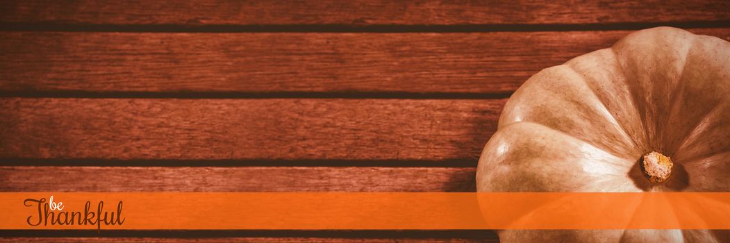 Thanksgiving greeting text against white pumpkin on wooden table during halloween