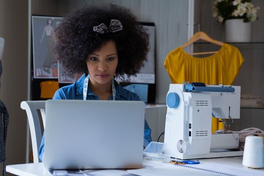 Female fashion designer working on laptop at table