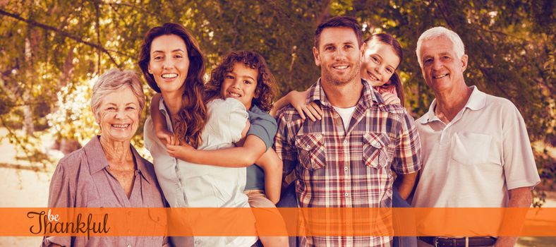 Thanksgiving greeting text against extended happy family standing together in park