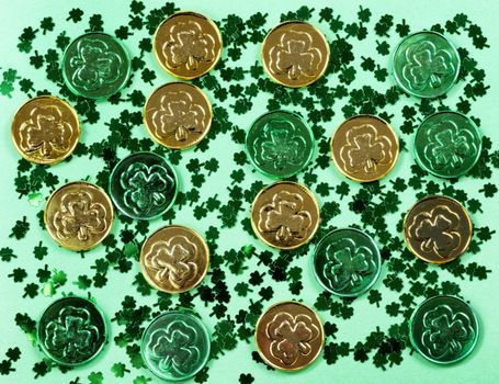 Saint Patricks Day with shamrocks and shiny coins on green background in filled frame format 