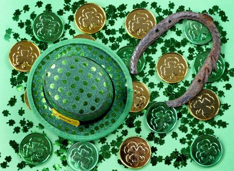 Saint Patricks Day with shamrocks, coins, hat and horseshoe on green background in filled frame format 