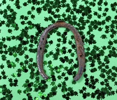 Saint Patricks Day with shamrocks and rusty horseshoe on green background in filled frame format 