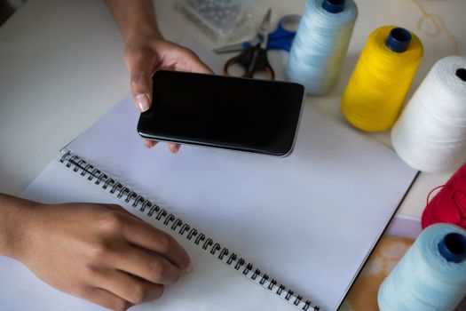 Fashion designer using mobile phone at desk at home