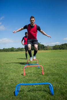 Soccer players practicing on obstacle in ground