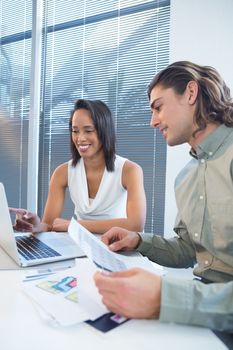 Business executives using laptop at desk in office