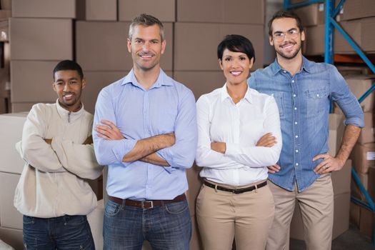 Warehouse workers smiling at camera in a large warehouse