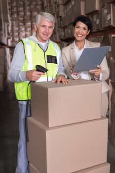 Warehouse worker scanning box with manager in a large warehouse