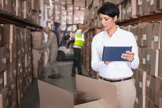 Pretty warehouse manager using tablet pc in a large warehouse