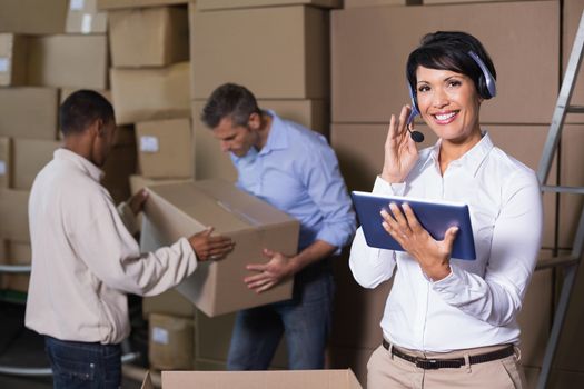 Pretty warehouse manager using tablet during busy period in a large warehouse