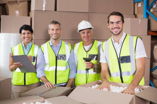 Warehouse workers in yellow vests preparing a shipment in a large warehouse