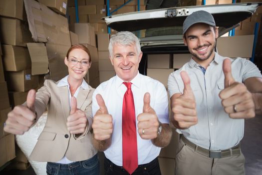 Warehouse managers and delivery driver smiling at camera in a large warehouse