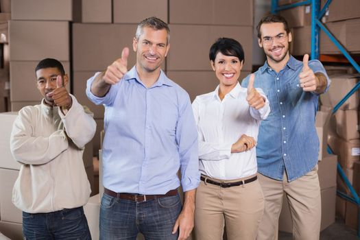 Warehouse workers smiling at camera in a large warehouse