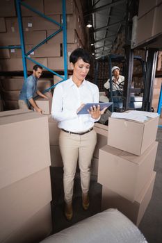 Warehouse manager using her tablet pc in a large warehouse