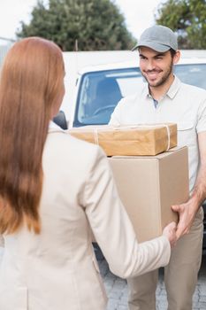 Delivery driver passing parcels to happy customer outside the warehouse