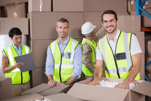 Warehouse workers in yellow vests preparing a shipment in a large warehouse